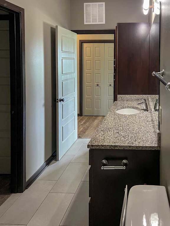a bathroom with a wide granite vanity sink and a tall storage cabinet