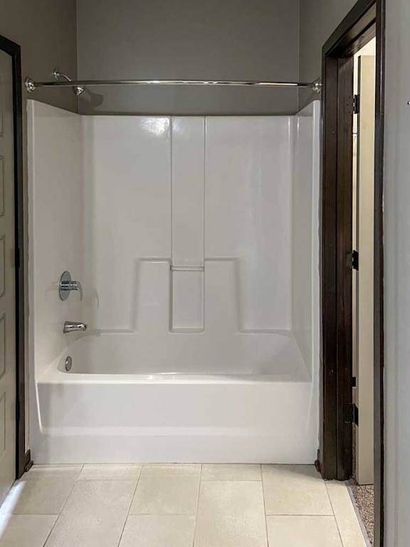 a bathroom with a tub shower and walk-in closet to the right