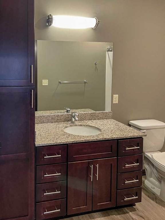 a bathroom with a granite vanity sink, mirror, and tall storage cabinet