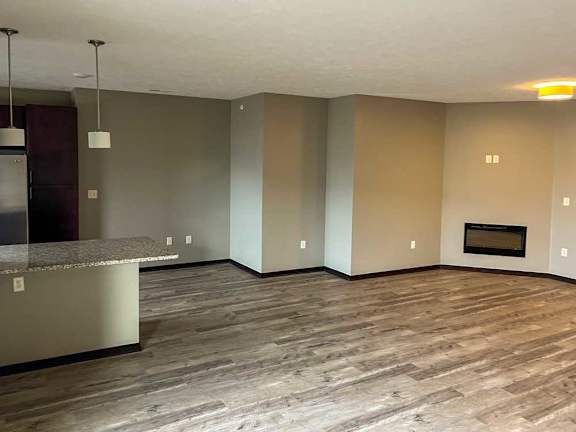 a living room with hardwood flooring and a fireplace next to the kitchen