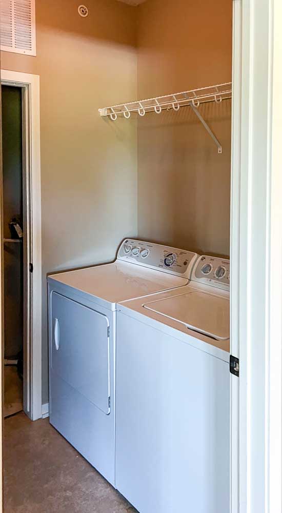 a side by side washer and dryer with overhead shelving in a double door closet at the top of the entryway