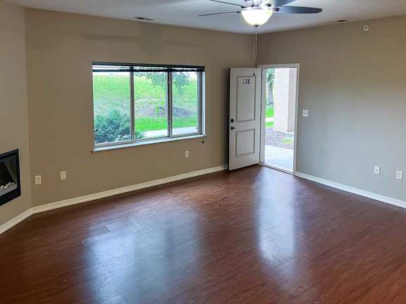 a living room with hardwood flooring, a large window, and a fireplace