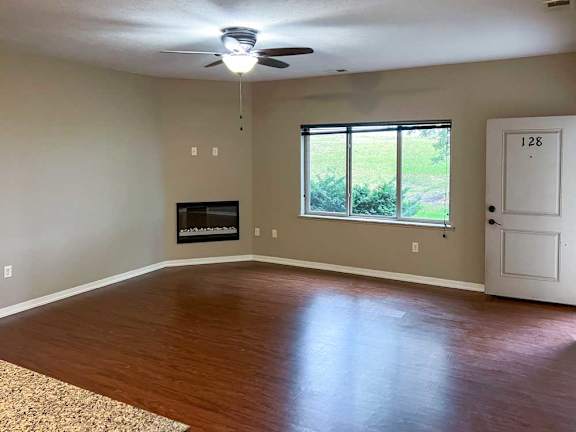 a living room with hardwood flooring, a large window, and a fireplace