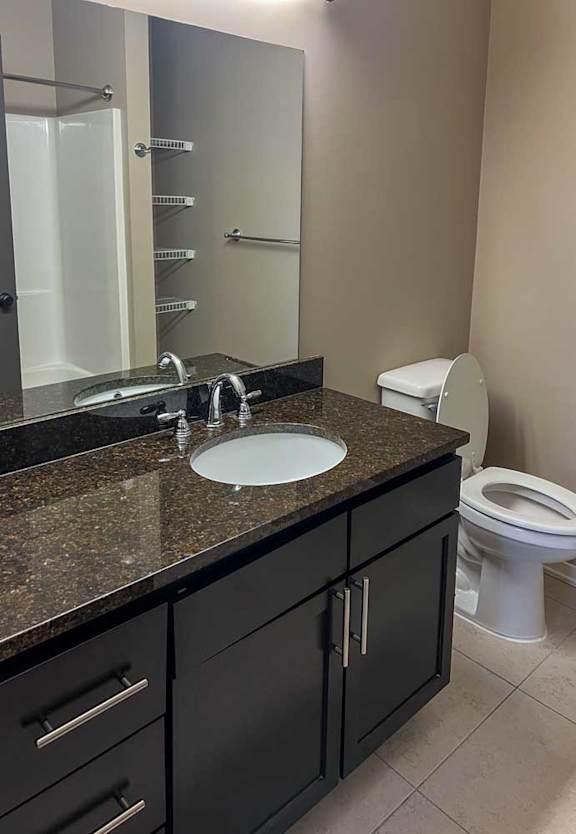 a bathroom with a granite vanity sink and large mirror