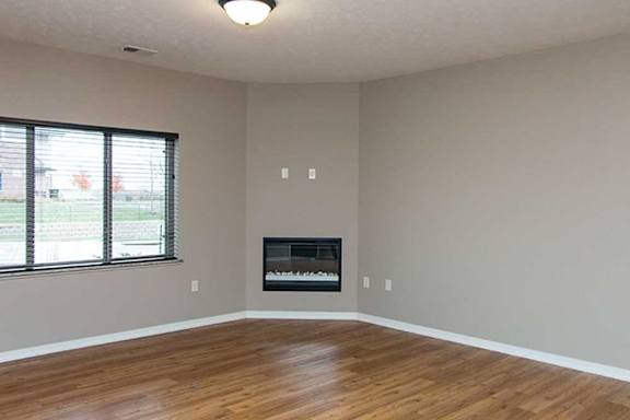 a living room with hardwood flooring, a large three-panel window, a ceiling fan, and a fireplace