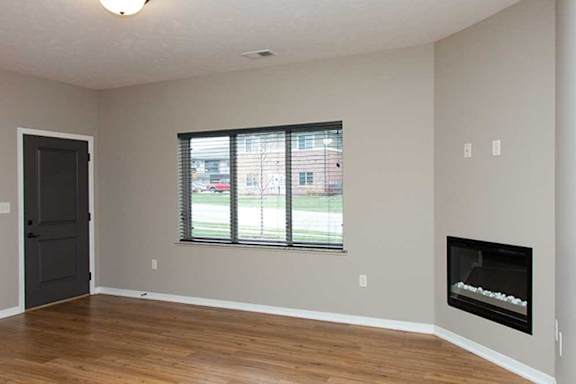 a living room with hardwood flooring, a large three-panel window, a ceiling fan, and a fireplace