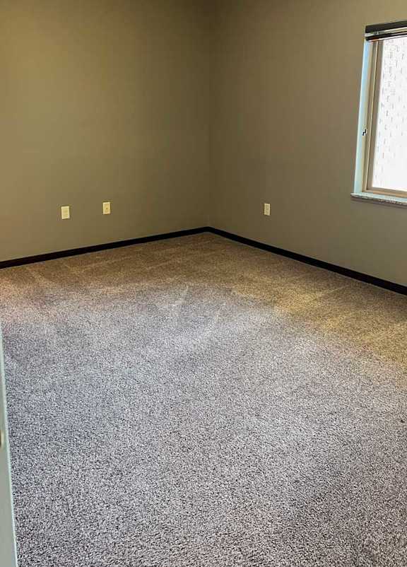 a bedroom with carpeted flooring and a window