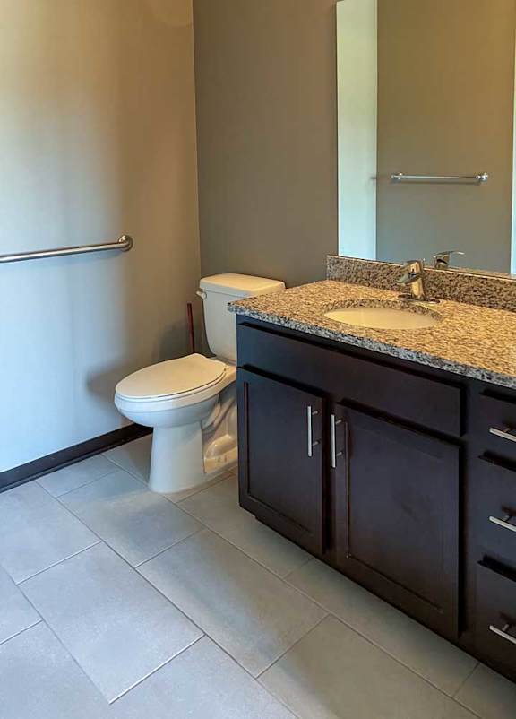 a bathroom with a granite vanity sink and a tall mirror