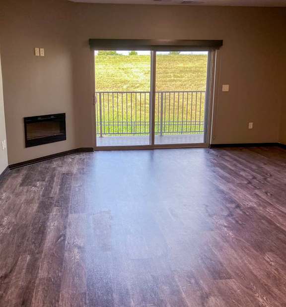 a living room with a fireplace and a sliding glass door to the balcony