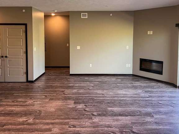 a living room with hard wood flooring, a fireplace, and a doorway to the hall for the bedroom and bathroom