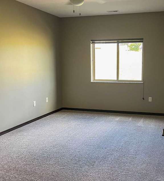 a bedroom with a window and a carpeted floor