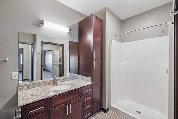 A bathroom with a sink, mirror, and shower.