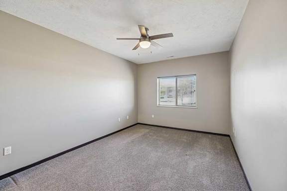 Empty room with a ceiling fan and a window.