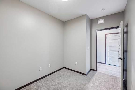 A room with a carpeted floor and a door on the right.