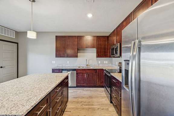 A kitchen with a granite countertop and stainless steel appliances.
