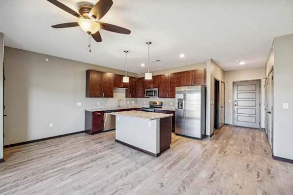 A modern kitchen with a wooden floor and a ceiling fan.