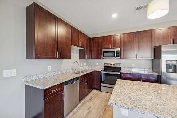 A kitchen with dark wood cabinets and granite countertops.