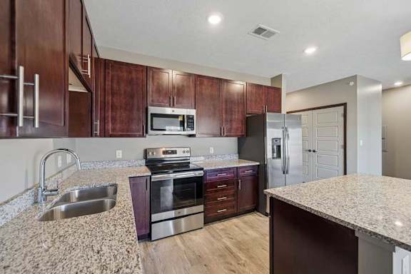 A kitchen with brown cabinets and granite countertops.