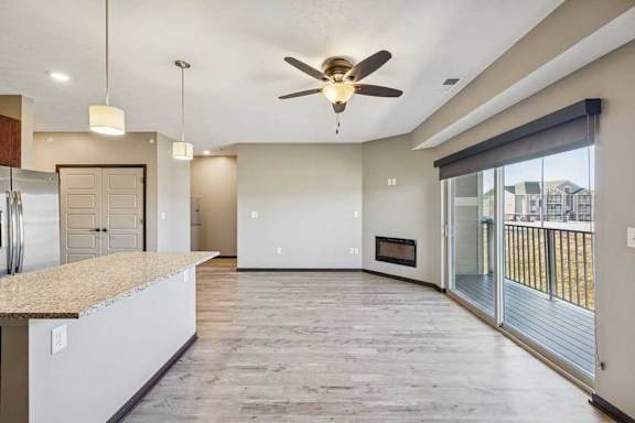 A spacious kitchen with a granite countertop and a ceiling fan.
