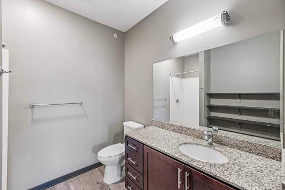 A bathroom with a toilet, sink, and mirror.