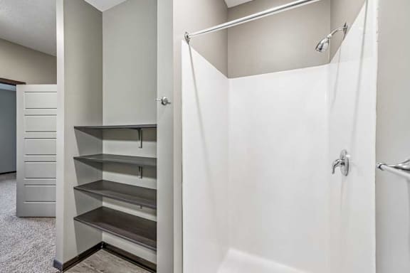 A white bathroom with a walk-in shower and a small kitchenette.