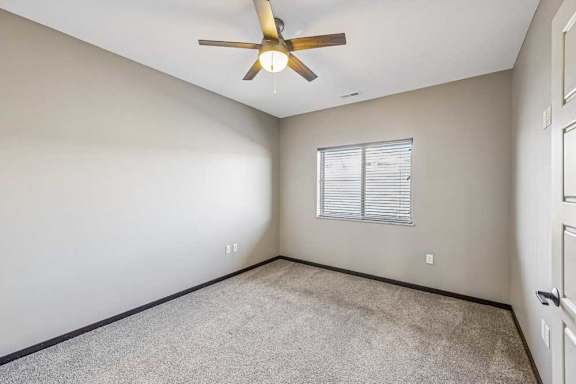 A room with a ceiling fan and a window with blinds.