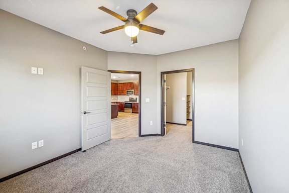 A room with a ceiling fan and carpeted floor.