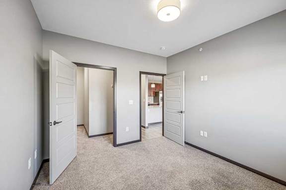 A room with three doors and a carpeted floor.