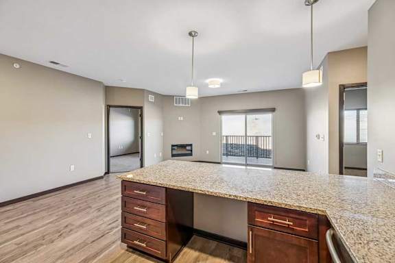 A spacious kitchen with a granite countertop and wooden cabinets.