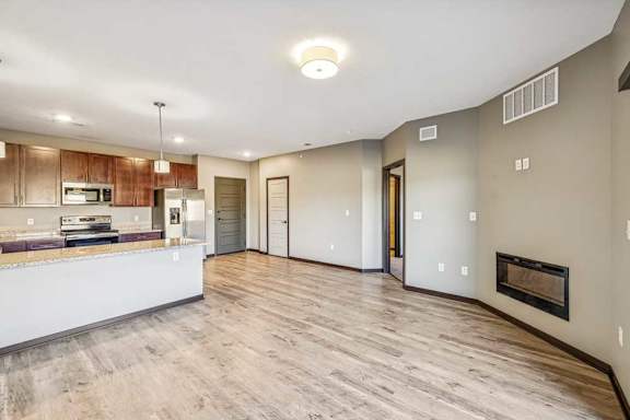 A spacious living room with a fireplace and a kitchen area in the background.