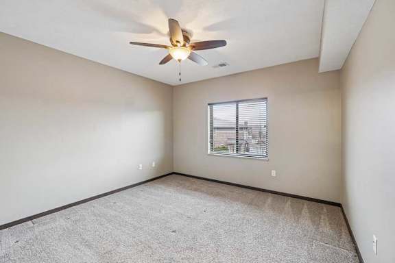 A room with a ceiling fan and a window with blinds.