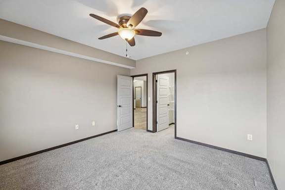 A room with a ceiling fan and carpeted floor.