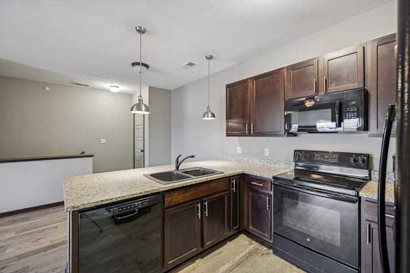 A kitchen with dark wood cabinets and black appliances.