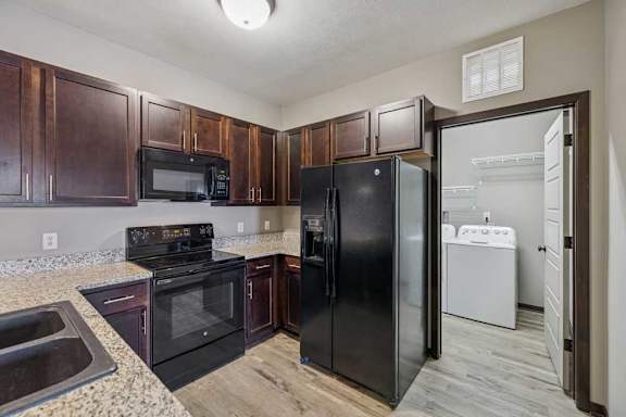 A kitchen with black appliances and wooden cabinets.