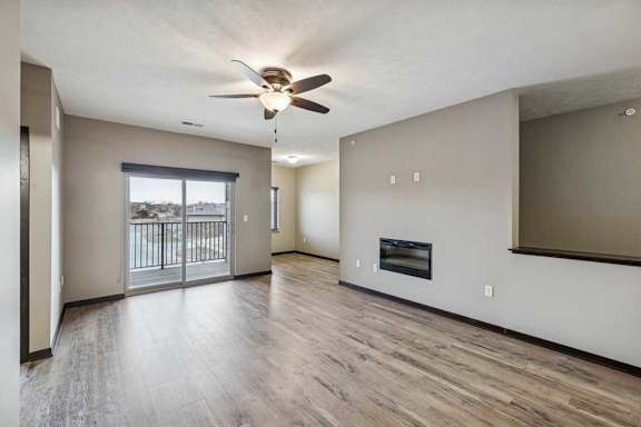 A spacious room with a ceiling fan and a balcony with a railing.