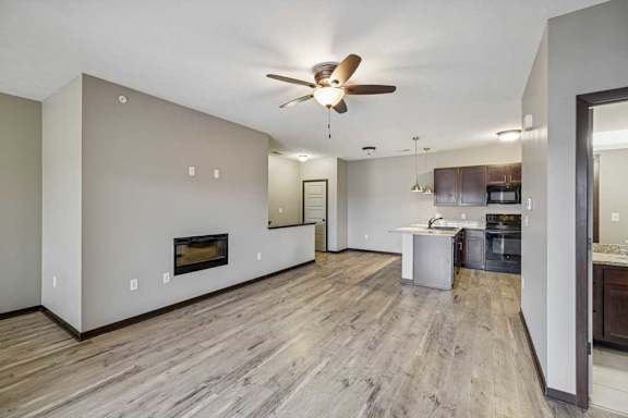 A spacious living room with a fireplace and a ceiling fan.