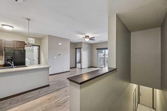 A kitchen with a refrigerator, sink, and a counter with a wood finish.