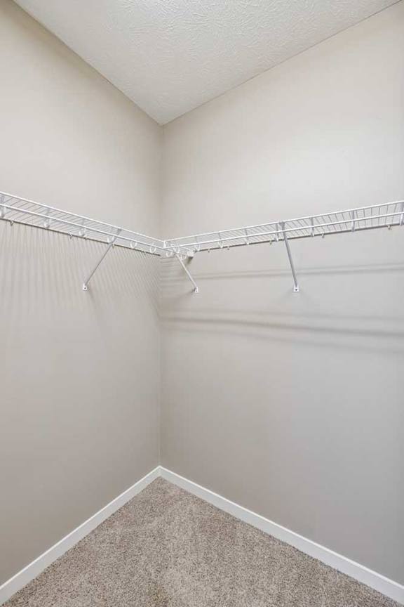 A large walk-in closet with white wire metal shelving