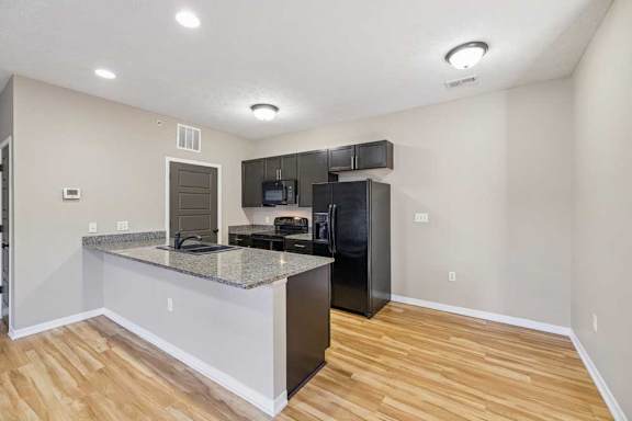 A kitchen with grey granite countertop and black appliances.
