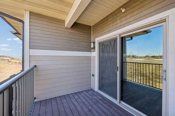 A deck with a sliding glass door leading to a backyard.