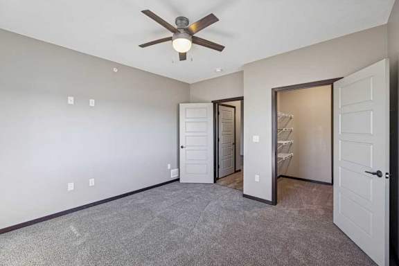 A room with a ceiling fan and a door leading to another room.