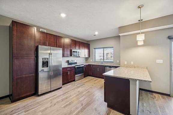 A kitchen with a refrigerator, microwave, and oven.
