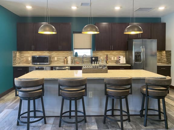 Clubhouse kitchen with large granite counter and 4 bar stools