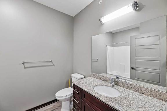 A bathroom with a toilet, sink, and mirror.