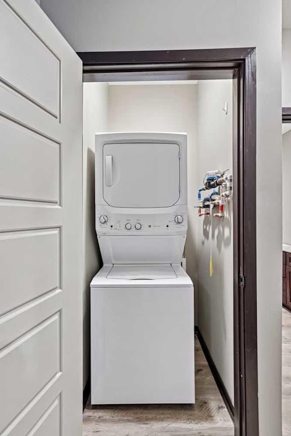 A white washing machine is in a small space between two doors.