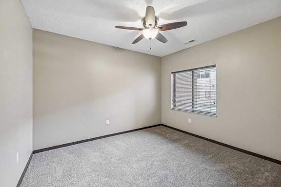 A room with a ceiling fan and a window with blinds.