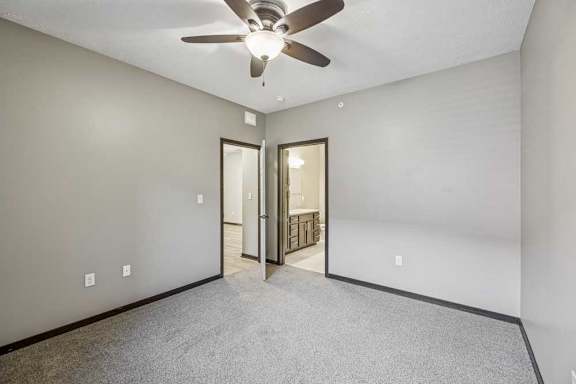 A room with a ceiling fan and a door leading to a hallway.
