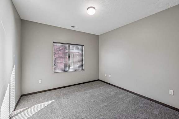 A room with a window and a carpeted floor.