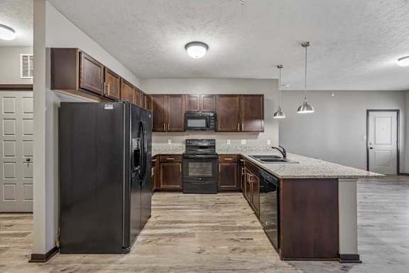 A kitchen with dark wood cabinets and a black refrigerator.