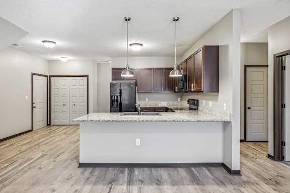 A modern kitchen with a marble island and dark wood cabinets.